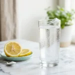 Glass of baking soda water with lemon on a white marble surface