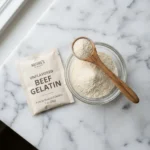 Beef gelatin benefits shown through powder and packet on white Carrara marble