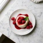 Classic panna cotta recipe with raspberry coulis on white Carrara marble