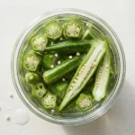 Strained okra water being poured into a glass through a small strainer